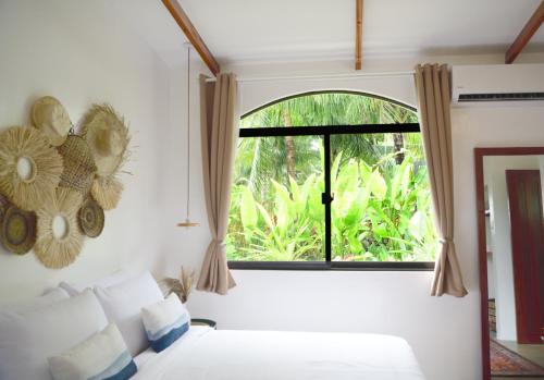 a bedroom with a bed and a large window at Villa Pura Vida Apartments Siargao in General Luna