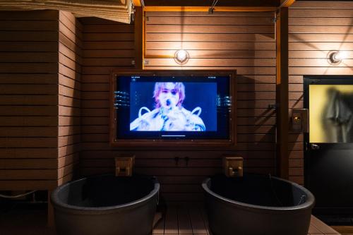 a tv in a room with two tubs and a televisionasteryasteryasteryastery at 安 Ann サウナで整う貸切の宿 USJ 万博会場近く 無料駐車場 寝室6 バスルーム4点 in Osaka