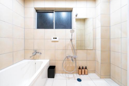 a bathroom with a tub and a shower at 安 Ann サウナで整う貸切の宿 USJ 万博会場近く 無料駐車場 寝室6 バスルーム4点 in Osaka