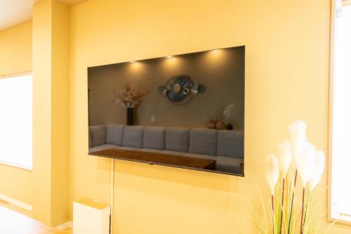 a living room with a couch on a yellow wall at 安 Ann サウナで整う貸切の宿 USJ 万博会場近く 無料駐車場 寝室6 バスルーム4点 in Osaka