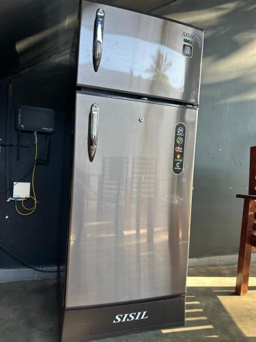 a metal refrigerator sitting next to a table at Surf Heavens in Dickwella