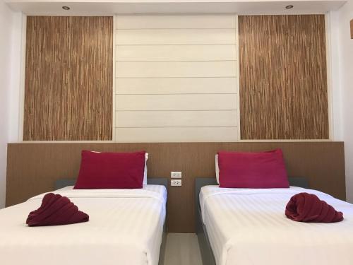 two beds with red pillows in a room at Tok Little Hut in Rayong