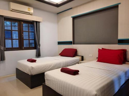 two beds in a room with red pillows on them at Tok Little Hut in Rayong
