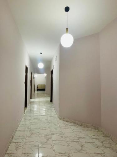 an empty hallway with white walls and floors and two lights at Uttara Luxury Apartment Near Airport & Metro in Dhaka