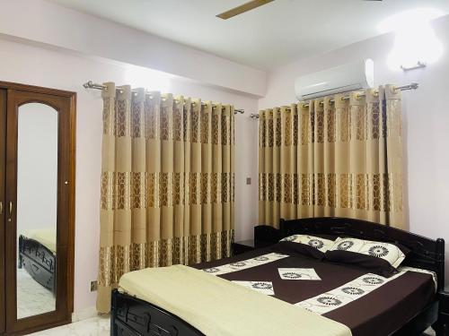 a bedroom with a bed and a mirror and curtains at Uttara Luxury Apartment Near Airport & Metro in Dhaka