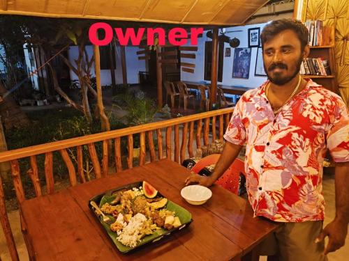 a man sitting at a table with a plate of food at Vibushan Guest House in Nilaveli