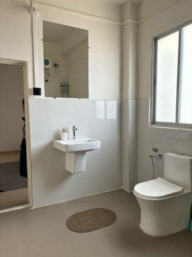a bathroom with a toilet and a sink and a mirror at The Local Guest House in Āīzawl