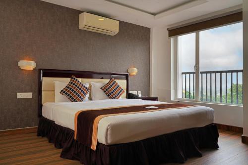 a bedroom with a large bed with a large window at KGA Elite Continental Hotel in Thiruvalla