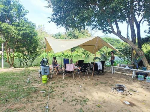 a tent with tables and chairs under a tree at แคมป์โจนส์ แก่งกระจาน Camp Jones in Ban Song Phi Nong