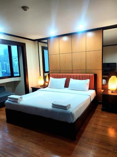 a bedroom with a large bed with two lamps at Affordable Serviced Apartment Nana - Omni Tower Sukhumvit location in Bangkok