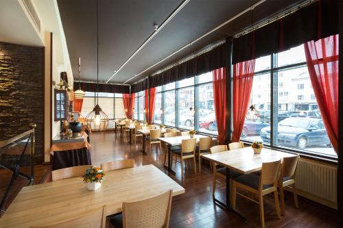 a restaurant with wooden tables and chairs and windows at Hotel Milton in Jyväskylä