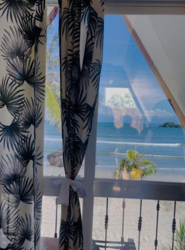 a window with a view of the beach and the ocean at Bolo Hills Beach Club And Residence in Alaminos