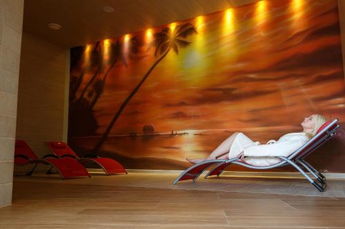 a woman sitting in a lounge chair in front of a mural at Pension U Golfu Cihelny in Karlovy Vary