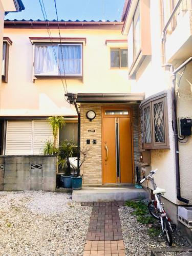 a house with a orange door and a bike parked outside at Nara House R3 in Kawagoe