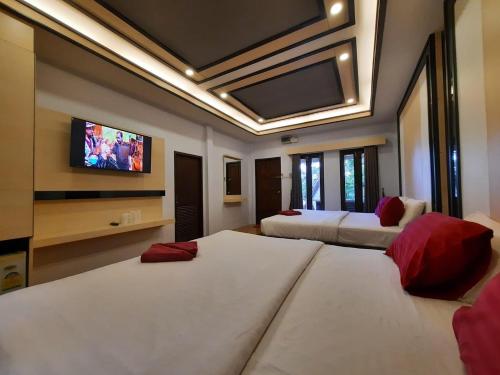 a bedroom with two beds and a flat screen tv at Tok Little Hut in Rayong