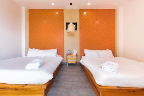 two twin beds in a room with a table at Be Youth Villa Đà Lạt - O'TEL in Da Lat