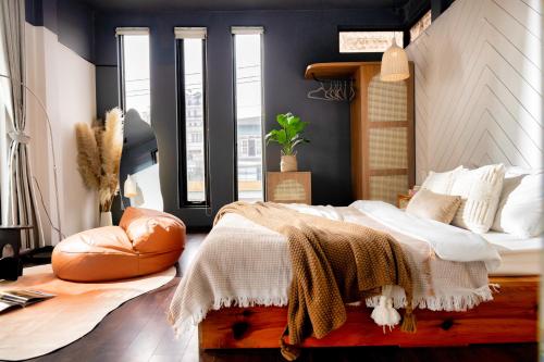 a bedroom with a bed and a chair and windows at Be Youth Villa Đà Lạt - O'TEL in Da Lat