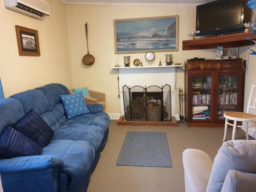 Una sala de estar con un sofá azul y un televisor. en Kirazz Holiday Homes, en Kingscote