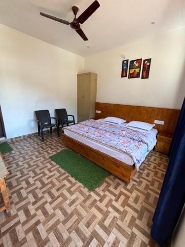 a bedroom with a bed with two chairs and a ceiling fan at Sunset Lagoon Dalhousie in Dalhousie