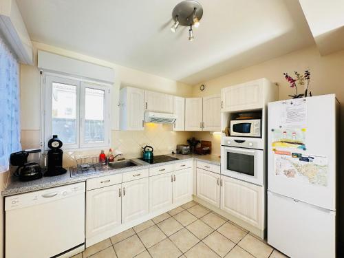 une cuisine avec des armoires blanches et un réfrigérateur blanc dans l'établissement Maison de vacances 6 pers, proche mer, Fouras - FR-1-709-85, à Fouras