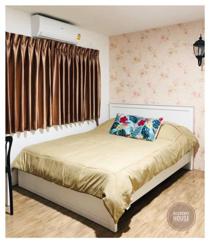 a bed with two pillows on it in a bedroom at Homestay Riceberry Ramintha in Ban Baen Phichit