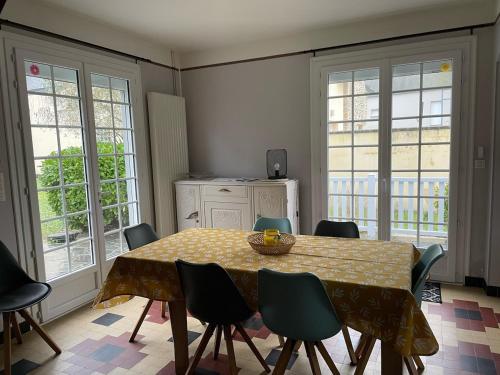 d'une salle à manger avec une table, des chaises et des fenêtres. dans l'établissement Les Ilous proche mer, à Hauteville-sur-Mer