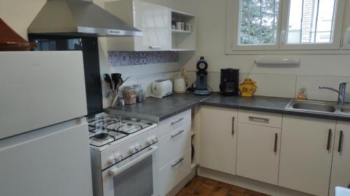 une cuisine avec des armoires blanches et un four à plaques de cuisson dans l'établissement Maison Balzac - 7 personnes quartier calme, à Châteauroux