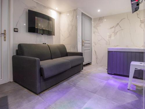 un salon avec un canapé et une télévision sur un mur dans l'établissement Le Ronali - Jacuzzi, à Manosque