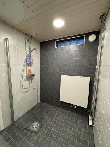 a bathroom with a shower with a white board on the wall at Ketunpesä Puijolla in Kuopio