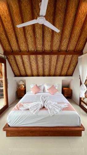 a bedroom with a white bed with a ceiling at Lila Sari Guest House with breakfast in Penginyahan