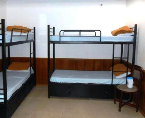 a room with three bunk beds and a table at RJ Inn in Kodaikānāl