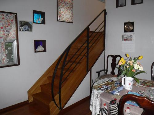 a room with a staircase and a table with flowers at グリーンハウス in Nanjo