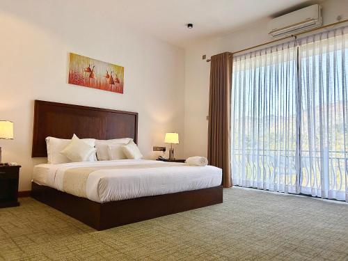 a bedroom with a large bed and a large window at The Marigold Hotel in Gampola