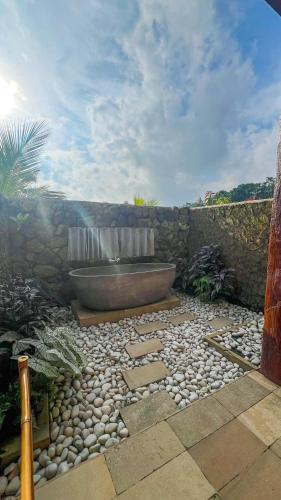 a bathroom with a tub and a stone wall at Lila Sari Guest House with breakfast in Penginyahan