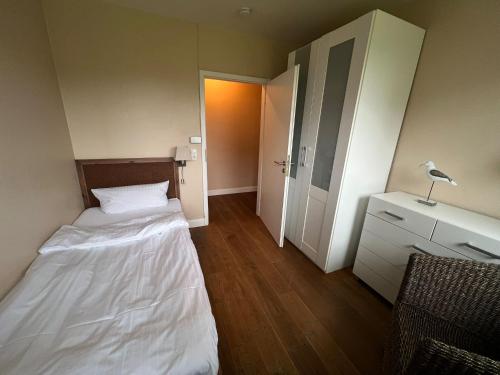 a small room with a bed and a closet at Hotel Hüttmann in Norddorf