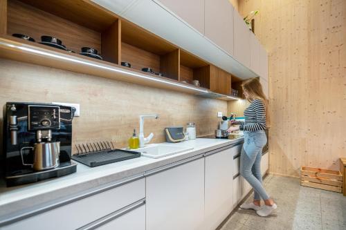 a woman standing at a counter in a kitchen at Chata Polomka s Jacuzzi - Vidíte deti na dvore z obývačky - Pri potoku - Výhľad na Polomské Očko in Brezno