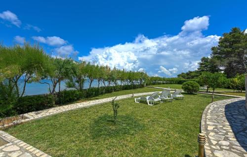 a row of white chairs sitting on a grass field at Stunning Apartment In Ugljan With Wifi in Ugljan