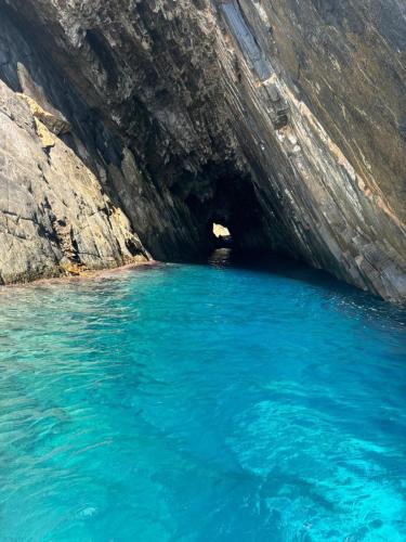 a cave with blue water in front of a cliff at MASUA HOUSE PRESTIGE-two minutes from the sea in Nebida