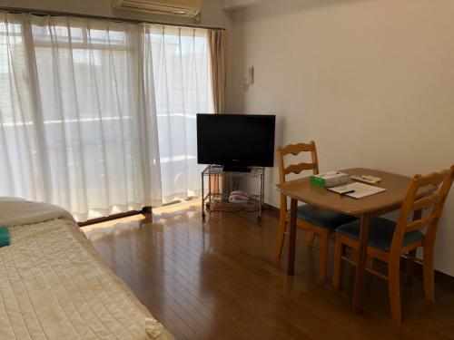 a room with a table and a television and a bed at Weekly Harbourview Mansion Main Building in Naha