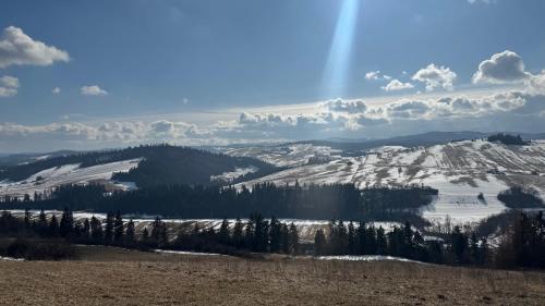 a snow covered mountain with a rainbow in the sky at Apartament Pieniny in Łapsze Niżne