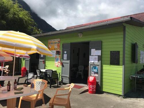 a green building with a table and an umbrella at Studio Au Coeur de Grand Ilet - Chez Tania! in Salazie