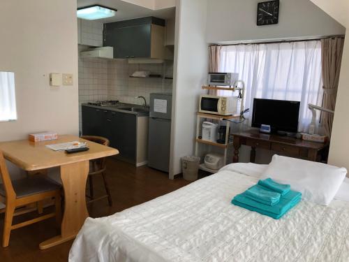 a bedroom with a bed and a table and a kitchen at Weekly Harbourview Mansion Main Building in Naha