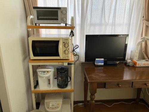 a room with a desk with a computer and a microwave at Weekly Harbourview Mansion Main Building in Naha