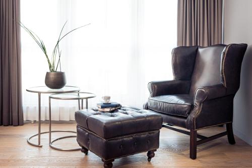 a leather chair and a stool in a living room at Parkhotel Langenthal in Langenthal