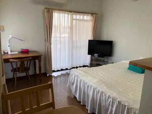 a bedroom with a bed and a desk and a television at Weekly Harbourview Mansion Main Building in Naha