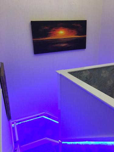 a purple room with a bath tub and a picture of a sunset at Jasmine House in Newquay