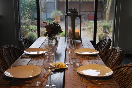 una mesa de madera con platos y copas de vino. en B&B De Hagmolenbeek Boekelo, en Boekelo