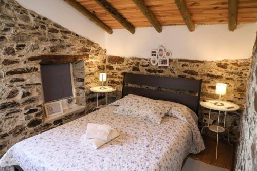 una camera da letto con un letto in un muro di pietra di Monte Cimeiro a Chaveirinha