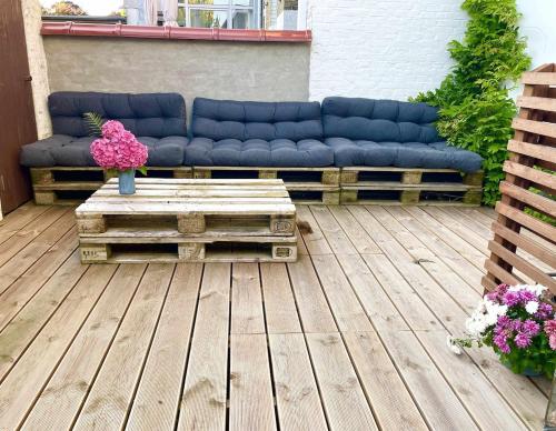 a blue couch sitting on a wooden deck with flowers at Charming Townhouse in the Heart of Haderslev in Haderslev