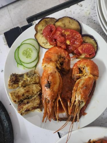 a plate of food with shrimp and vegetables on a table at TheLight Villa in Trou dʼ Eau Douce